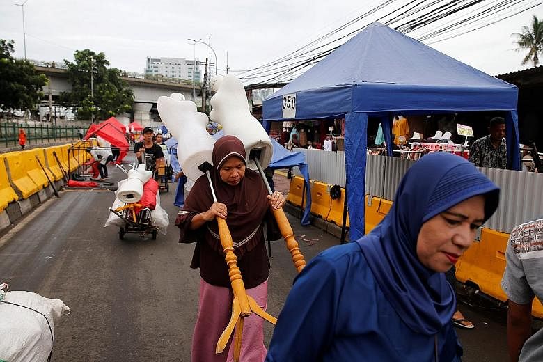 Street vendors preparing to set up their stalls in the Tanah Abang market in Jakarta. The busy area (below) in the congested Indonesian capital also has a train station and when the new governor, Anies Baswedan, closed off one of the busiest streets 