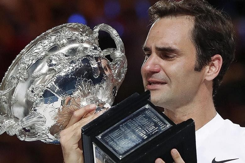 A tearful Roger Federer admiring the Norman Brookes trophy after beating Marin Cilic in the final yesterday at Melbourne Park.