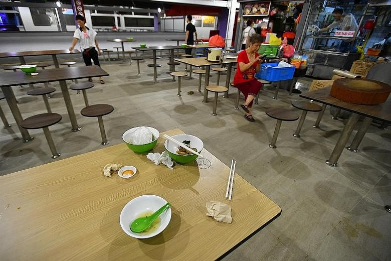 Left: A customer at Marsiling Mall Hawker Centre carrying her food without using a tray. Above: At Bukit Merah Central food centre, used crockery and cutlery are left behind on tables.
