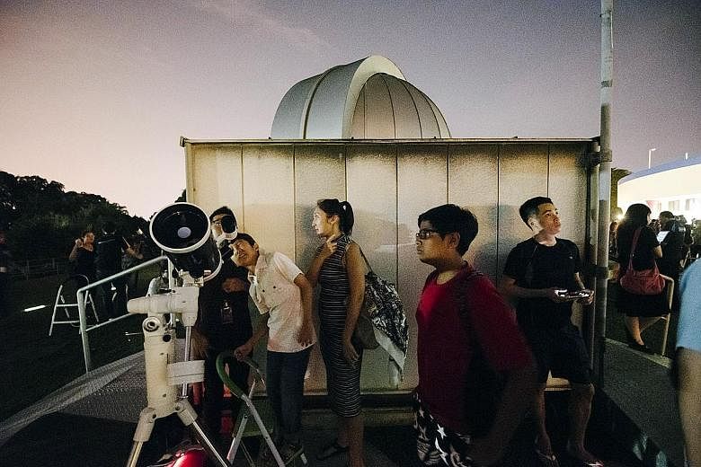 Left: Last night's supermoon seen at 9.50pm from Upper East Coast Road. Below: People gathered at the Science Centre, where a special viewing session was held last night. The last time a lunar eclipse, blue moon and supermoon took place at the same t