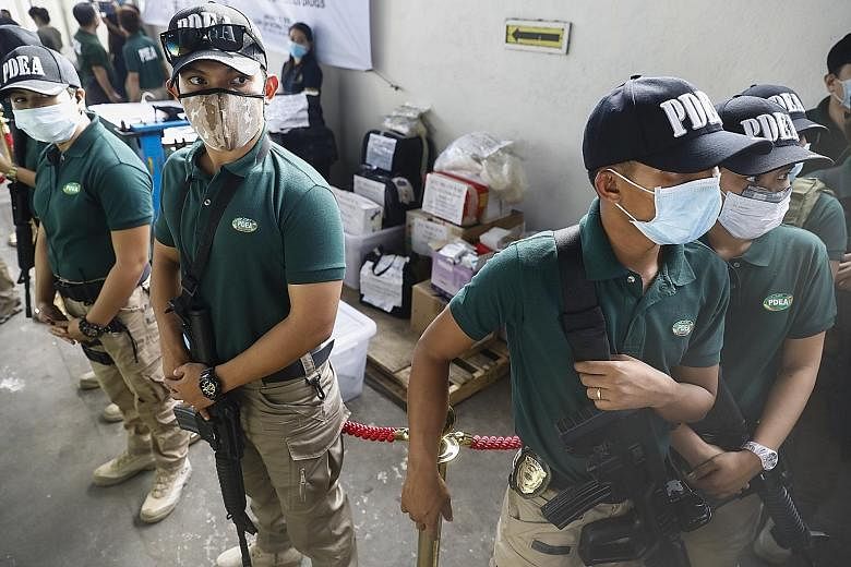 Drug enforcement agents guarding drugs that have been seized. Philippine police resumed their anti-drug campaign on Monday with visits to the homes of users and dealers to convince them to surrender.