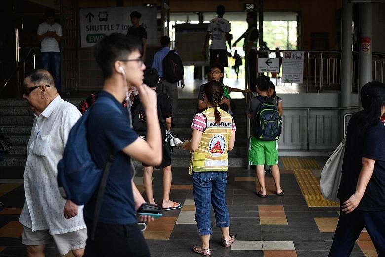 A Community Emergency Response Team volunteer in a yellow safety vest helping to direct commuters at Pasir Ris MRT station during a planned closure of some East-West Line stations on Sunday.