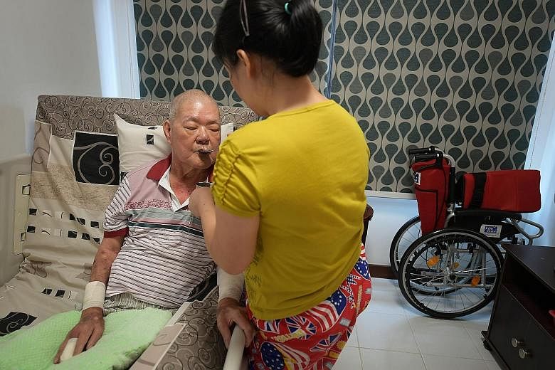 Retiree Choo Kim Sua, whose diabetes led to kidney failure and a double leg amputation, drinking water with the help of domestic helper Thu Zar Myint. Under the H2H programme, a nurse and social worker provided home nursing and caregiver support, and
