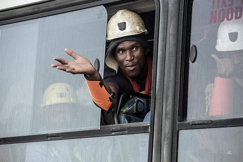 A miner waving from a bus after being rescued from the Beatrix gold mine, near the city of Welkom in South Africa, yesterday. The 955 miners were stuck for about 30 hours after a power cut.