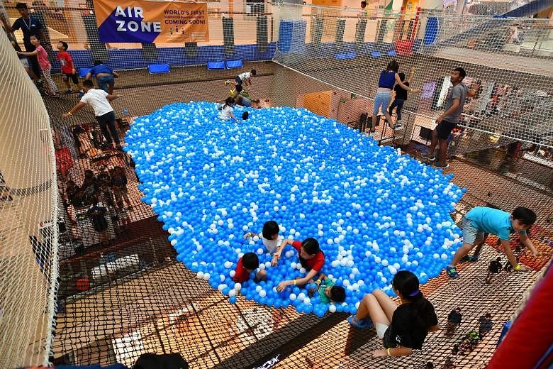 Children under seven must be accompanied by an adult to enter the suspended ball pit at City Square Mall. Left: A ball pit "lifeguard" attending to a child yesterday.
