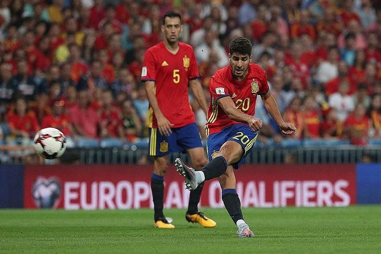 Spain's Marco Asensio striking the ball in a friendly against Italy in September, as team-mate Sergio Busquets watches on. Officials are in talks to prevent the risk of the 2010 World Cup winners' expulsion from this year's competition in Russia, aft