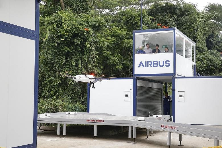 A drone landing on the maintenance platform after being loaded with a parcel during the demonstration at the National University of Singapore yesterday, as Skyways staff watched from a control tower.
