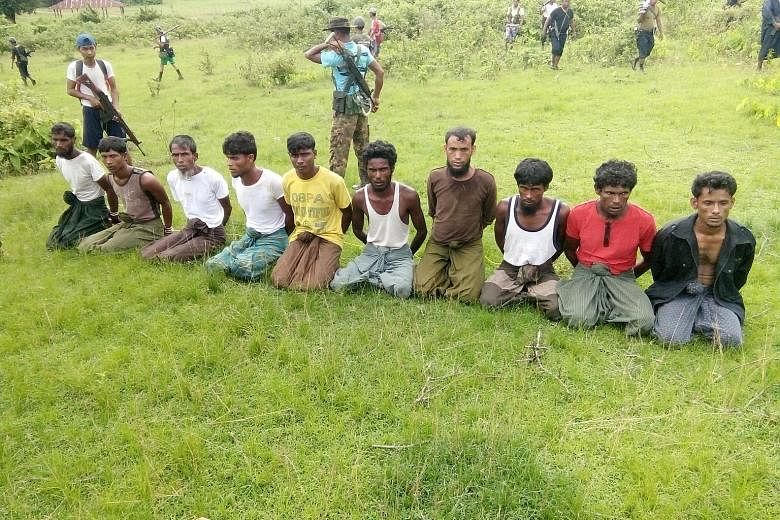 Above: Human bones in a shallow grave in Inn Din village on Dec 8 last year. Below: Ten Rohingya Muslim men kneeling, with their hands bound, ahead of their execution on Sept 2.