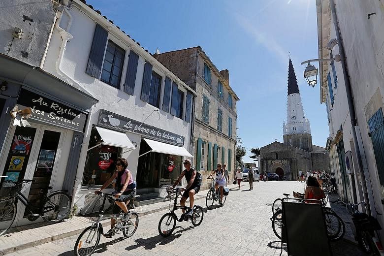 Tourists riding down a street on Re Island, France. Personal trainer Annette Lang recommends renting a bike for an hour or two, if you are in an urban destination that has a bike-share programme, to explore the waterfront or other scenic parts of tow