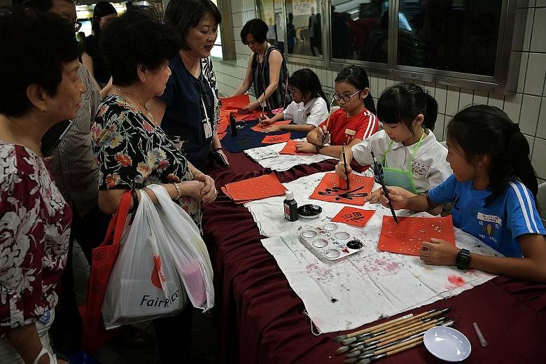 Pupils from Pei Chun Public School demonstrating the art of Chinese calligraphy at Toa Payoh MRT station yesterday as part of the Chinese New Year festivities. The pieces of artwork were then given to members of the public. The activity was organised
