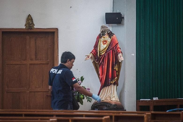 A police investigator in the Yogyakarta Catholic church where a radical Islamist had attacked people attending a service on Sunday. The man also decapitated a Virgin Mary statue with his sword.