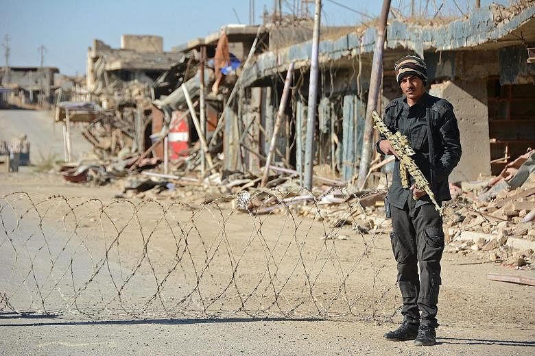 A member of the Iraqi forces guarding a checkpoint in the northern Iraqi city of Baiji. The one-time industrial hub has been reduced to a devastated ghost city in the fight against ISIS.
