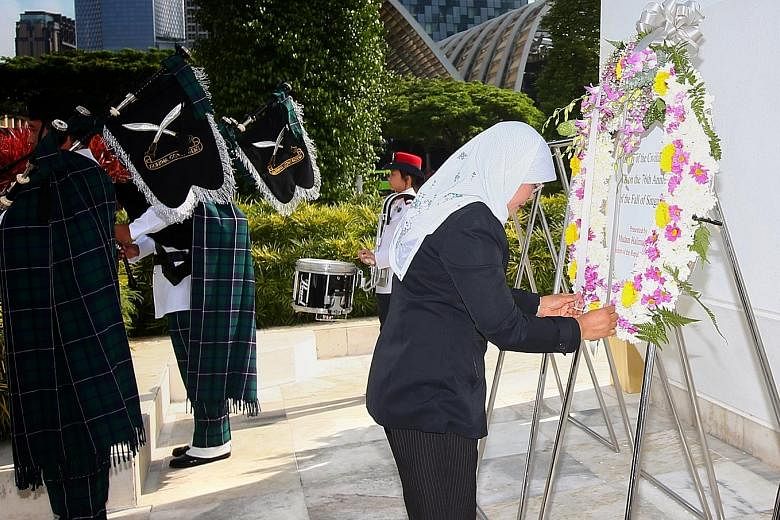 Above: President Halimah Yacob, guest of honour at the 51st War Memorial Service, laying a wreath at the War Memorial Park on Total Defence Day yesterday. Right: Guests at yesterday's service paying their respects at the Civilian War Memorial, which 