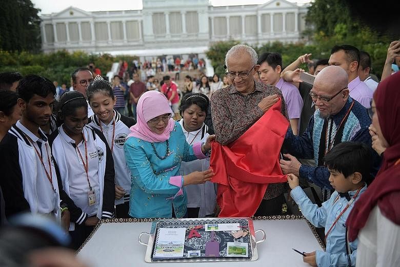 President Halimah Yacob unveiling the President's Challenge memorabilia during the Istana's Open House yesterday, the second day of Chinese New Year. With her is her husband, Mr Mohamed Abdullah Alhabshee.