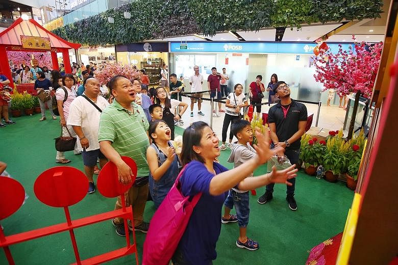 Mrs Cindy Goh spinning the Wheel of Fortune yesterday at Seletar Mall's Fortune Garden as her family cheered her on. Seletar Mall invited about 50 beneficiaries of The Straits Times School Pocket Money Fund (STSPMF) and their family members to an aft