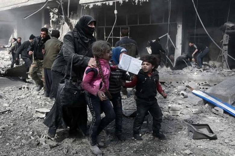 Civilians running for cover from the bombing in the rebel-held town of Hammuriyeh, Eastern Ghouta, on Monday. A total of 127 civilians, including 39 children, were killed in Monday's bombardment, making it the bloodiest day for the Syrian enclave in 