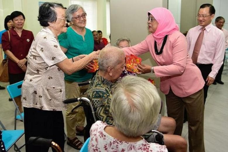 President Halimah Yacob giving mandarin oranges to Madam Boh Cheak Wah, 90, at the Serangoon Moral Family Services Centre yesterday. During her visit to the centre in Serangoon Avenue 2, Madam Halimah also launched a food donation drive where food it