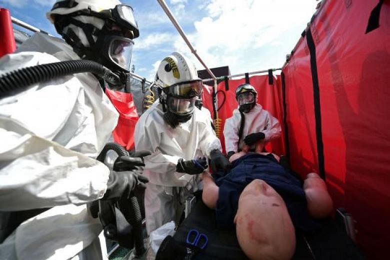 ST reporter Cheryl Tee (second from left) helps to "decontaminate a casualty" during a drill on board the Orca. The SCDF Marine Command is responsible for marine fire and rescue incidents and containment of chemical agents. 