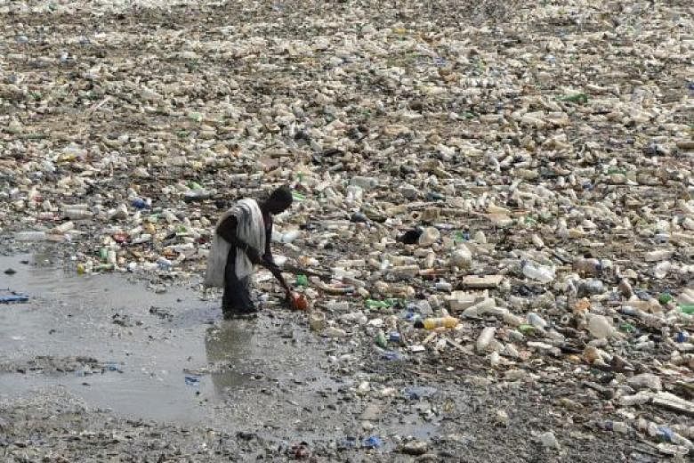 A man collecting plastic from a waste water evacuation canal in the Ebrie Lagoon in Abidjan, Cote d'Ivoire, on Monday. Between five million and 13 million tonnes of the world's plastic waste end up in the oceans.