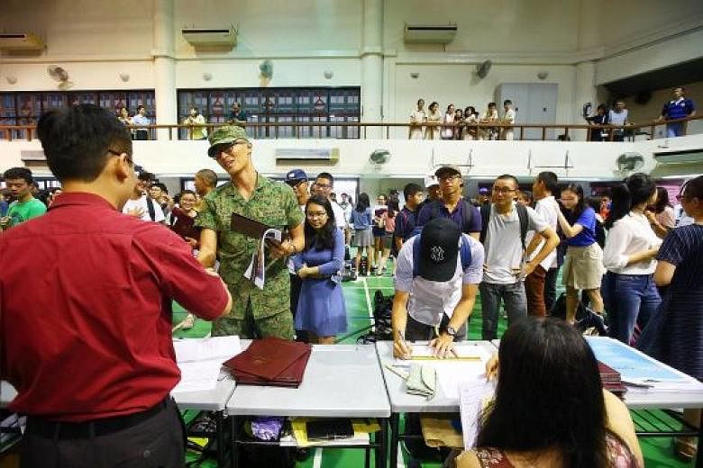 Hwa Chong Junior College students, some in their national service uniforms, lining up in the school hall to get their A-level results.