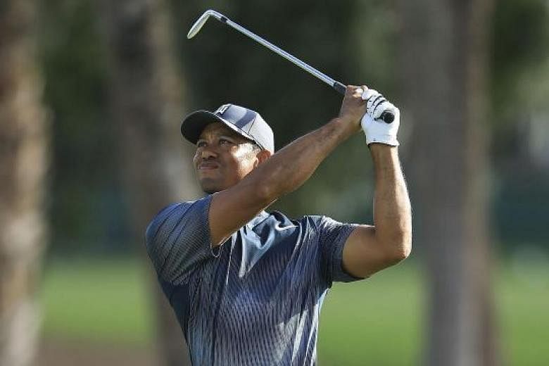 Tiger Woods playing his approach shot on the 14th hole in the first round of the Honda Classic on Thursday. He mixed three birdies with a bogey and a double bogey in difficult, blustery conditions to match his best opening round in four PGA National 