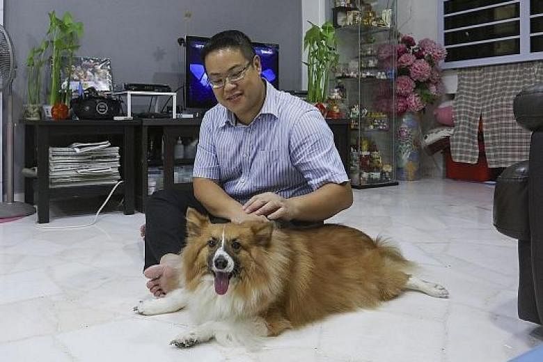 Mr Amos Koh with his dog Louie in his Bukit Batok flat. He says that after getting a fixed-rate package, the monthly instalment for his home has been reduced by $59 (from $1,567 to $1,508).
