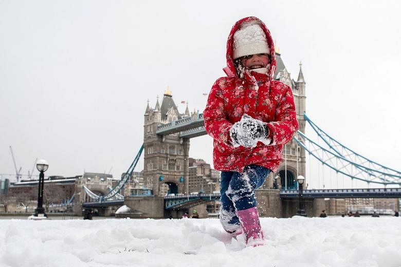 A girl playing close to London's Tower Bridge yesterday as Britain is hit by sub-zero temperatures. More heavy snow is expected in the coming days.