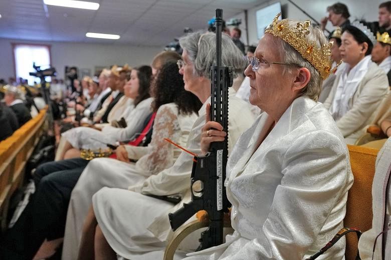 Worshippers at the World Peace and Unification Sanctuary in Newfoundland, Pennsylvania, holding weapons during a service on Wednesday. Hundreds of worshippers gathered inside the church at a blessing ceremony for couples featuring their AR-15 rifles.