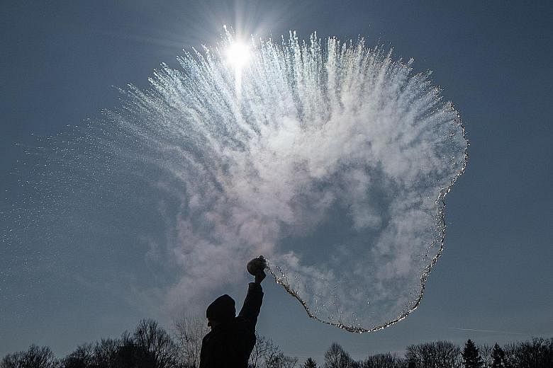 Top: A woman creates an instant sparkling cloud of snow by throwing hot water into the freezing cold air on Thursday in Berlin, Germany. Meanwhile, an ongoing blizzard has affected air, road and train transport around Europe. Above: A sculpture of ho