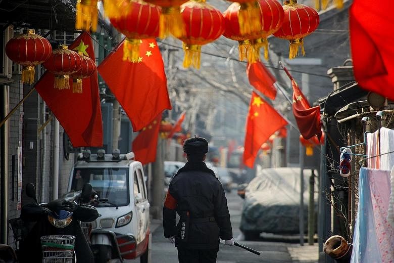A security guard patrolling a residential alley near Beijing's Great Hall of the People, the venue of the plenary session of the National People's Congress, yesterday.