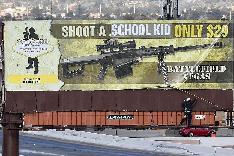 Workers removing a billboard in Las Vegas on Thursday after vandals struck. The words "school kid" were put over ".50 caliber", and "Defend lives reform laws" was added to the ad for a machine gun range.