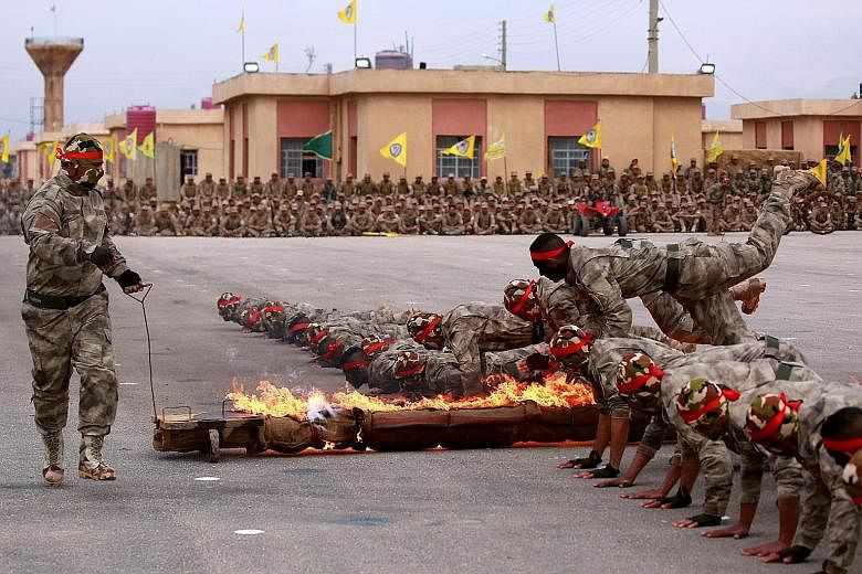 Arab and Kurdish fighters from the Syrian Democratic Forces taking part in a graduation ceremony after completing their military training in Syria's north-eastern Qamishli region on Thursday. They are part of the United States-led military campaign a