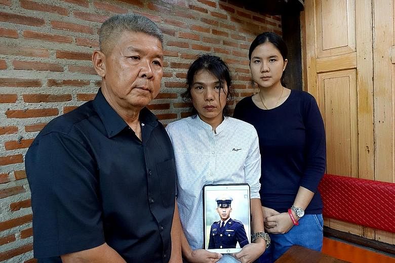 Mrs Sukanya Tanyakan holding a photo of her late son Pakapong Tanyakan in cadet uniform, with husband Pichet Tanyakan and daughter Supicha Tanyakan. Although heart failure was the official reason given for the boy's death while training at Thailand's