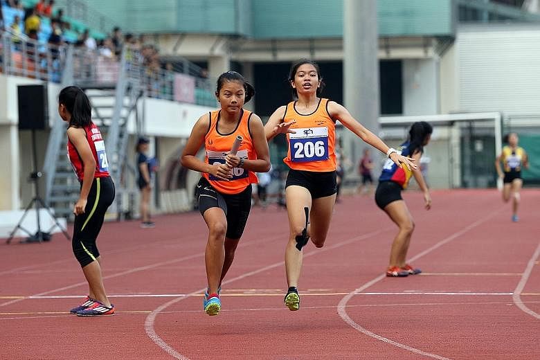 Singapore Sports School's Diane Pragasam passing the baton to team-mate Palada Tang in the A Division girls' 4x200m relay final yesterday. The team won the event and will compete in the 4x100m and 4x400m at Bishan Stadium today.