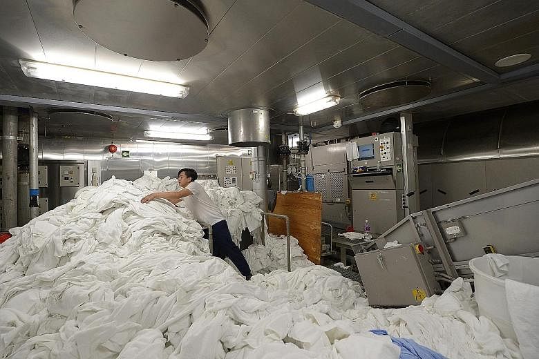 A worker tackles an enormous load in the laundry room, deep in the belly of the ship. The 17-strong crew are in charge of washing the cloths that cover everything from guest beds to the tables of restaurants. A cleaner using a jet spray to sanitise a
