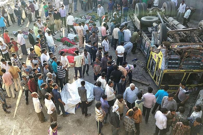 Onlookers gathering around the bodies of passengers who had been travelling in a lorry that plunged off a bridge in western India yesterday. 	At least 30 people - mostly women and children - died when the lorry, carrying a wedding party, fell off the