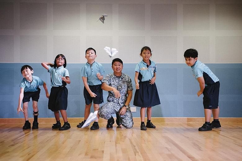 Lieutenant-Colonel Tay Kok Ann, 45, head of the Experience and Engagement Group for RSAF50@Heartlands, throwing paper planes with Primary 2 pupils from First Toa Payoh Primary School on Monday during an engagement activity to celebrate the Republic o