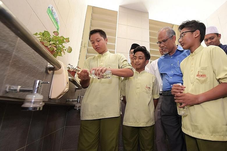 Muhammad Afif Sahernizam, 13, showing Minister for the Environment and Water Resources Masagos Zulkifli how he practises his ablutions in a water-efficient way with a small bottle of water at the Al-Mawaddah Mosque in Sengkang.