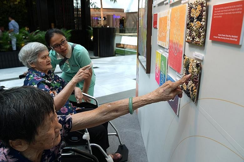 Madam Kwan Ah Geok (foreground), 91, and Madam Joan Oliviero, 82, from Econ Healthcare looking at artworks by other nursing home residents.