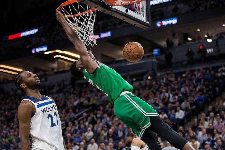 Boston Celtics guard Jaylen Brown dunking in the third quarter as Minnesota Timberwolves guard Andrew Wiggins looks on. Brown fell heavily on his back and head after this dunk, silencing the crowd, only to receive a standing ovation when he eventuall