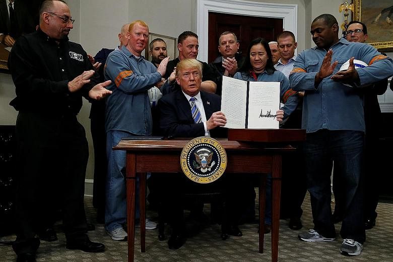 US President Donald Trump, flanked by steel and aluminium workers, at a signing ceremony at the White House in Washington on Thursday to establish tariffs on imports of steel and aluminium. The tariffs go into effect on March 23.