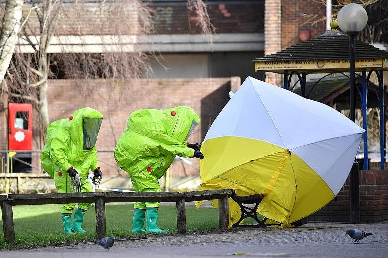 Emergency service officers in hazard suits fixing a tent over the bench where double agent Sergei Skripal and his daughter Yulia were found poisoned on Sunday. British detectives were scrambling to find the source of the nerve agent used.