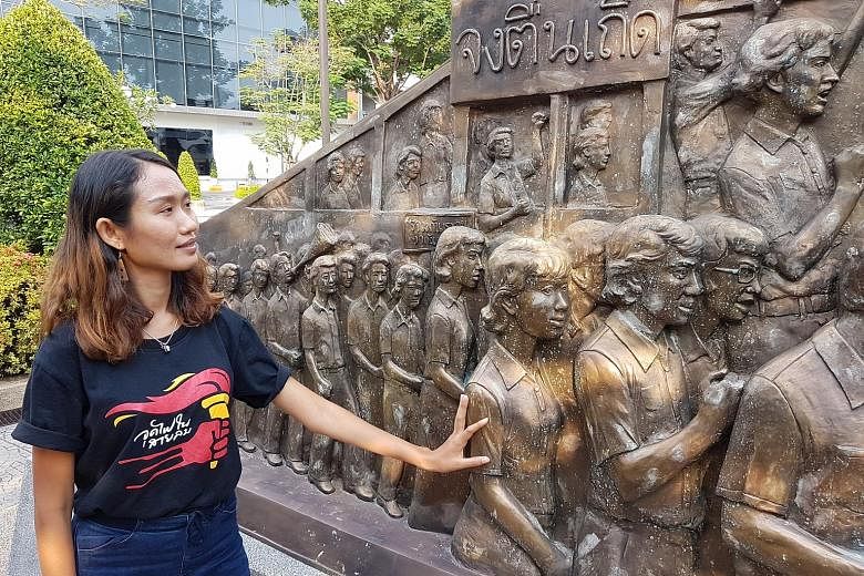 Ms Chonthicha Jangrew, who fronts the Democracy Restoration Group, stands by a pro-democracy sculpture in Thammasat University in Bangkok.