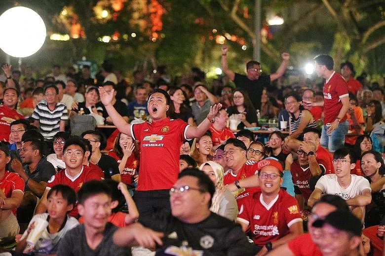 Manchester United supporters cheering after their team opened the scoring against Liverpool last night. Close to 1,000 people gathered to catch the live telecast at the lawn in front of Victoria Memorial Hall.