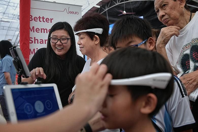 At the launch of the Digital Volunteers initiative yesterday was resident Chew Li Fong (second from left), 66, who wore a SenzeBand which detects brainwaves, as she played mental games on a tablet device.