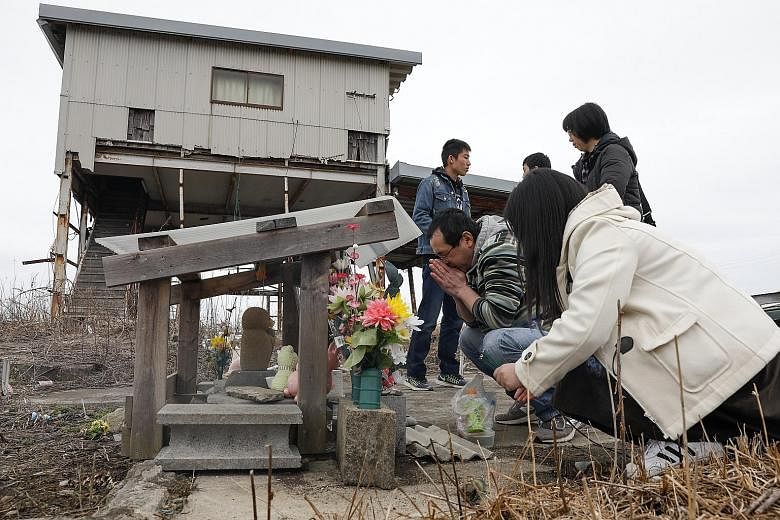 Family members who lost their loved ones during the Fukushima disaster offering prayers yesterday. More than 73,000 people are still displaced as a result of the disaster that hit Japan's north-eastern coast on March 11, 2011.