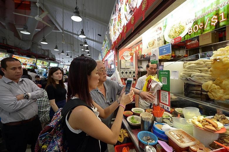 Customer Neo Ann Chee, 36, paying for her lunch at the Tanjong Pagar Plaza Market and Food Centre using the QR code payment system offered at the stall. Of the 50 stalls there, 45 display the Nets QR code and have Nets' card readers to let consumers 