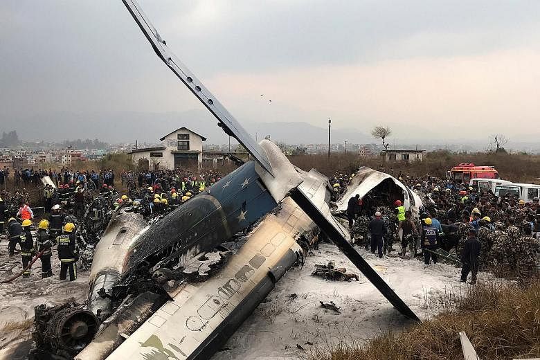 Rescue workers at the scene of the plane wreckage at the Kathmandu airport yesterday. The aircraft, operated by US-Bangla Airlines, was on a flight from Dhaka when it hit an airport fence and burst into flames, according to the airport. It had 71 peo