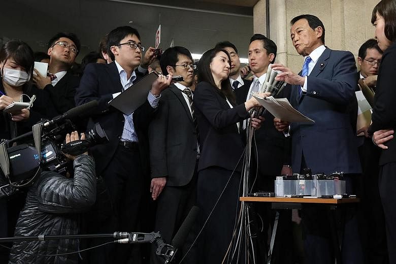 Finance Minister Taro Aso (in blue) yesterday apologised for his ministry's actions, but said he did not intend to step down. He said several officials at his ministry's division in charge of the land sale were involved in altering the documents to m