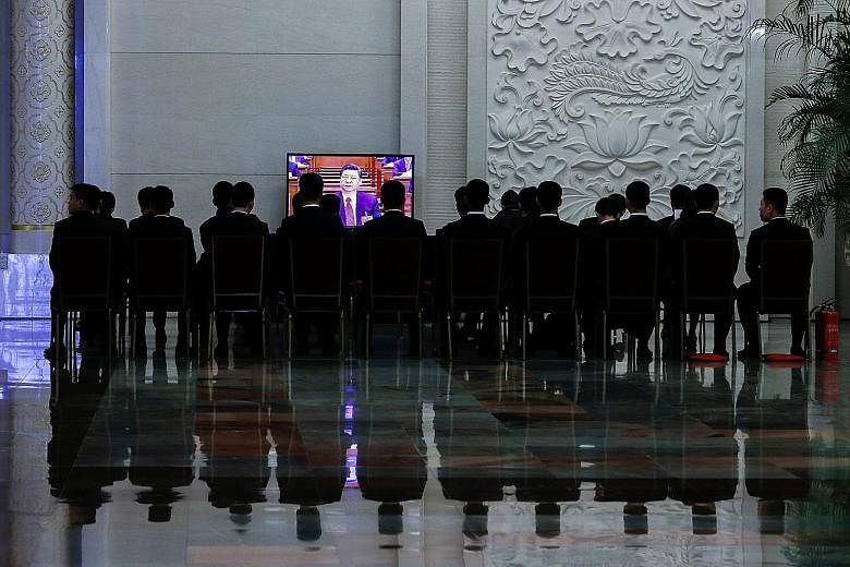 Chinese security officers and staff watching a live telecast of President Xi Jinping at the fourth plenary session of the National People's Congress at the Great Hall of the People in Beijing yesterday.